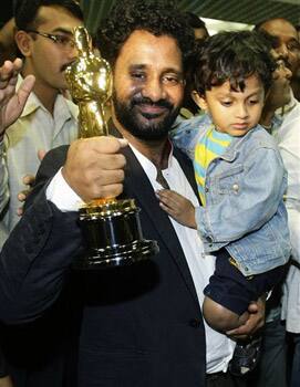 Oscar award winner Resul Pookutty, left, holding the Oscar statuette, hugs an unidentified child as actor Irrfan Khan, right, looks on after they arrived at the international airport in Mumbai.