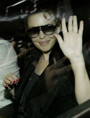 ustralian singer Kylie Minogue gestures towards photographers after arriving at the international airport in Mumbai, India.