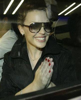 Australian singer Kylie Minogue gestures towards photographers after arriving at the international airport in Mumbai, India.