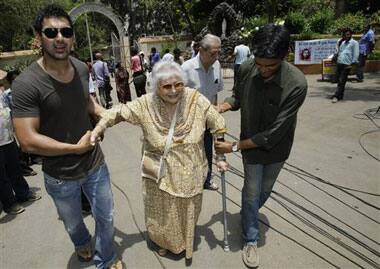 Bollywood actor John Abraham, left, helps an elderly voter Gulus Patel, 83, to a polling station in Mumbai