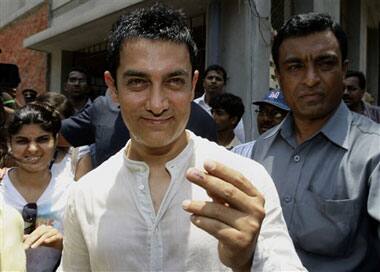 Bollywood actor Aamir Khan shows the indelible ink mark on his finger after casting his vote at a polling station in Mumbai