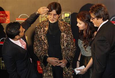 Bollywood star Abhishek Bachchan touches a wax figure of Amitabh Bachchan as Aiswarya Rai Bachchan Amitabh, second from right, and Amitach Bachchan, right, look on before a circus show at the 10th Int