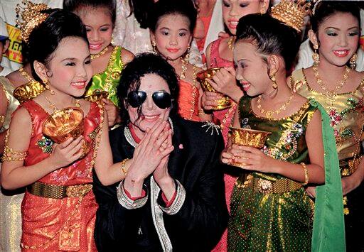 In this early November 1996 file photo, pop star Michael Jackson is greeted by Thai children in traditional dress as he arrives ahead of his concert in Bangkok, Thailand.