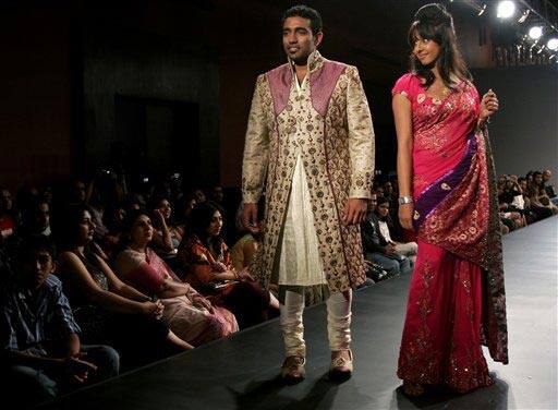 Indian cricketer Robin Uthappa, left, and actor Sanjaana, right, present creations by Sanjay and Shammy Choraria at the Bangalore Fashion Week.