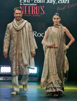 Indian golfer Jeev Milkha Singh, left, walks the ramp with a model presenting creations by Rocky S at the Bangalore Fashion Week 2009