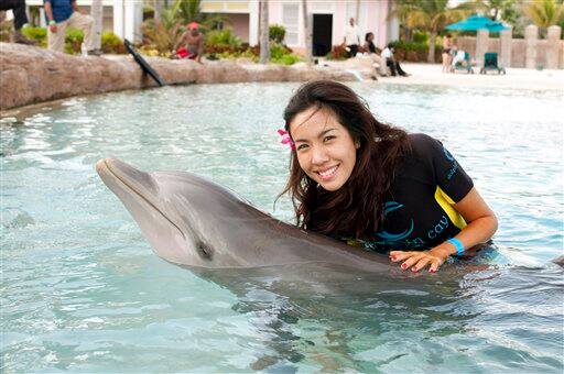 In this photo provided by the Miss Universe Organization, Chutima Durongdej, Miss Thailand 2009, hugs a dolphin at Dolphin Cay in Atlantis, Paradise Island, Bahamas on Saturday, August 8, 2009.