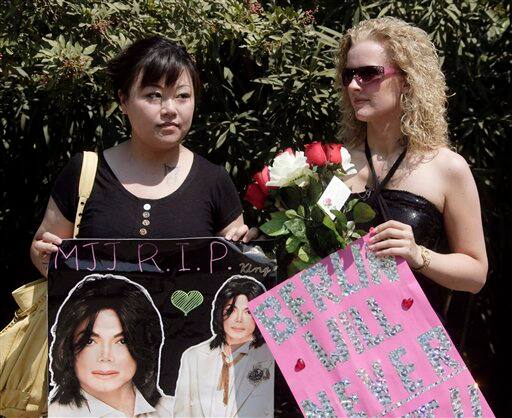 Hu Hui Lin, left, and Svenja Maniak from Berlin Germany hold signs while waiting outside the Jackson family home in the Encino section of Los Angeles