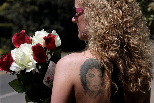 With a Michael Jackson tattoo on her back, Svenja Maniak from Berlin, Germany, holds flowers while waiting outside the Jackson family home in the Encino section of Los Angeles