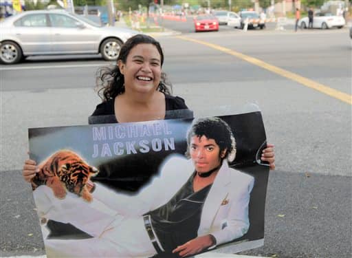 Maria Martinez, Riverside, Calif., is seen holding a Michael Jackson poster one city block away from the controlled entrance to Forest Lawn Memorial Park in Glendale, Calif.