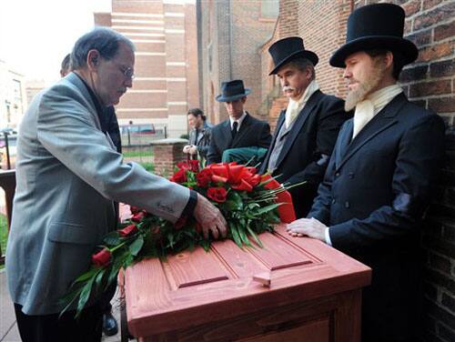 Jeff Jerome, left, curator of the Poe House and Museum, places flowers on a casket outside Westminster Hall in Baltimore during a reenactment of author Edgar Allan Poe's funeral