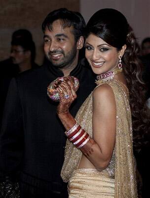 Bollywood actress Shilpa Shetty, right, and her husband Raj Kundra pose for the media as they arrive to host their wedding reception in Mumbai.