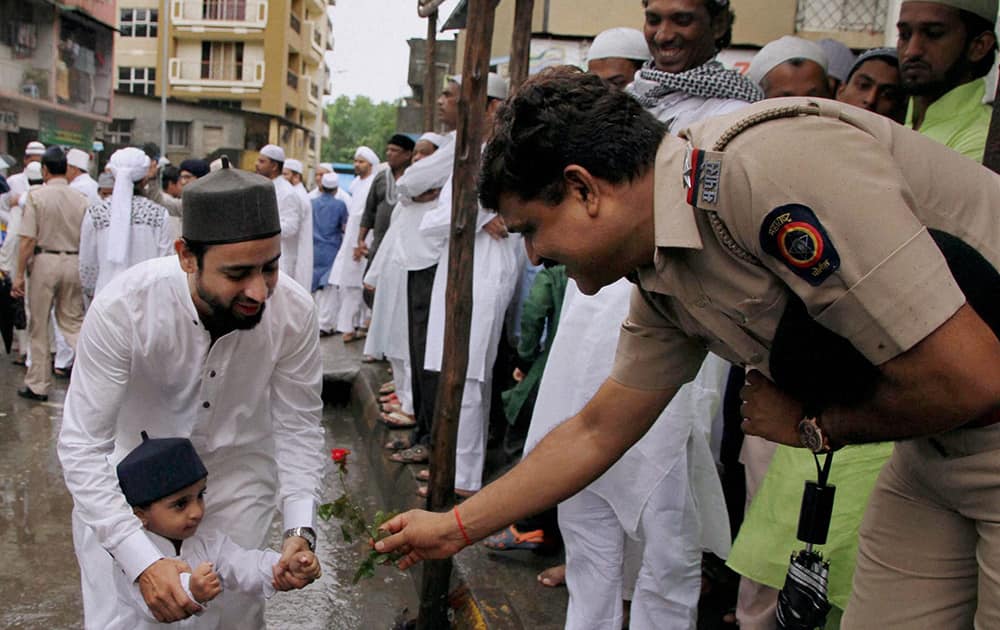 A police man greets offers rose to a child as he greet Muslims on the occasion of `Eid-Ul-Fitr` in Mumbai.