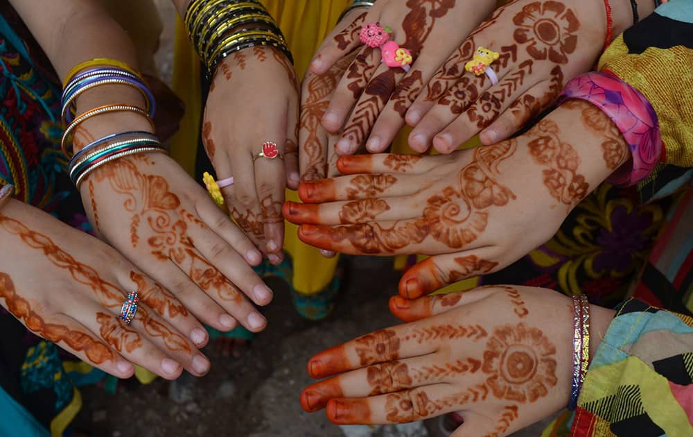 Pakistani girls show their hands painted with henna ahead of the Muslim holiday of Eid al-Fitr in Peshawar, Pakistan.