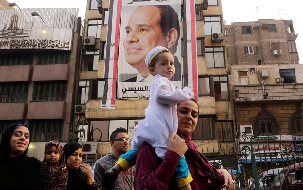 An Egyptian family walks under a giant banner supporting Egyptian President Abdel Fattah el-Sissi as they celebrate Eid al-Fitr, marking the end of the Muslim holy fasting month of Ramadan, in Cairo, Egypt.