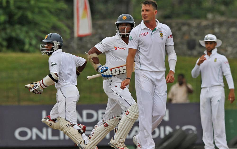 Sri Lankan batsmen Kaushal Silva, left, and Kumar Sangakkara, centre, run between the wickets as South African bowler Dale Steyn watches during the fourth day of the second test cricket match between South Africa and Sri Lanka in Colombo, Sri Lanka.