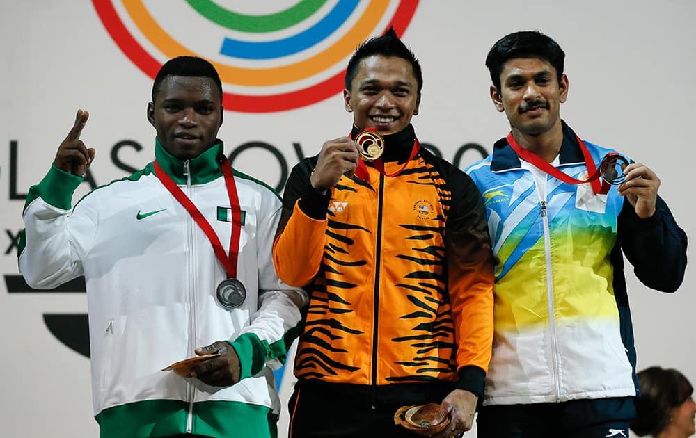 Gold medalist Mohd Hafifi Mansor of Malaysia, centre, with Yinka Ayenuwa of Nigeria, left, silver medal and Omkar Otari of India with the bronze medal pose for photographs after the medal ceremony for the men`s 69 kg weightlifting competition at the Commonwealth Games Glasgow 2014.