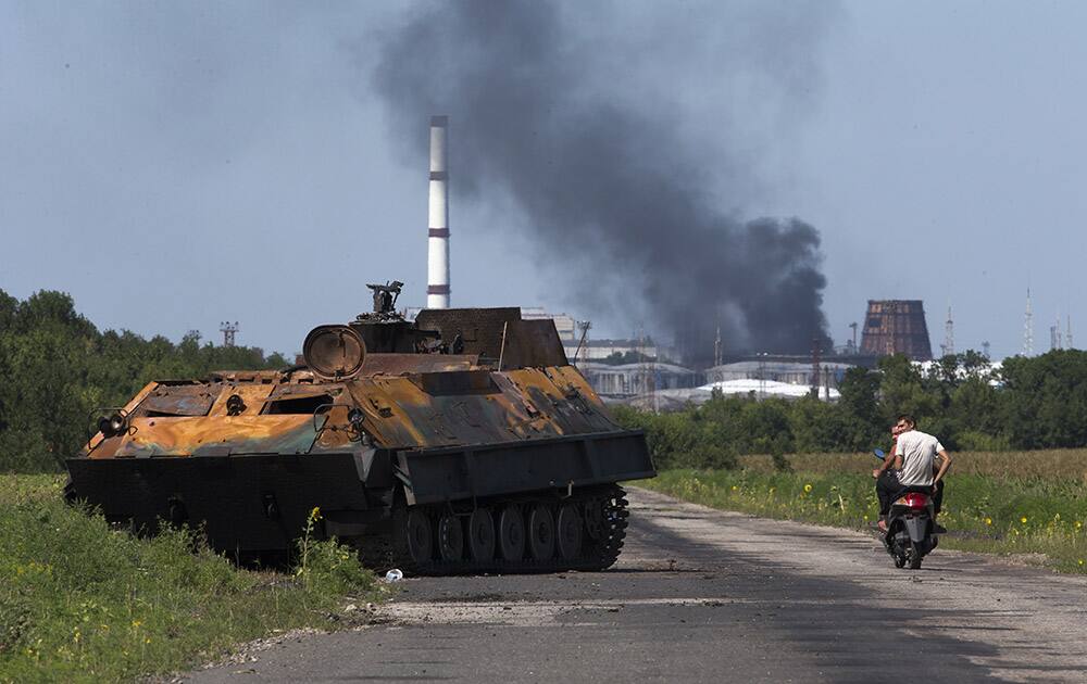 People ride a scooter past a destroyed pro-Russian fighters` APC near the city of Lisichansk, Luhansk region, eastern Ukraine.
