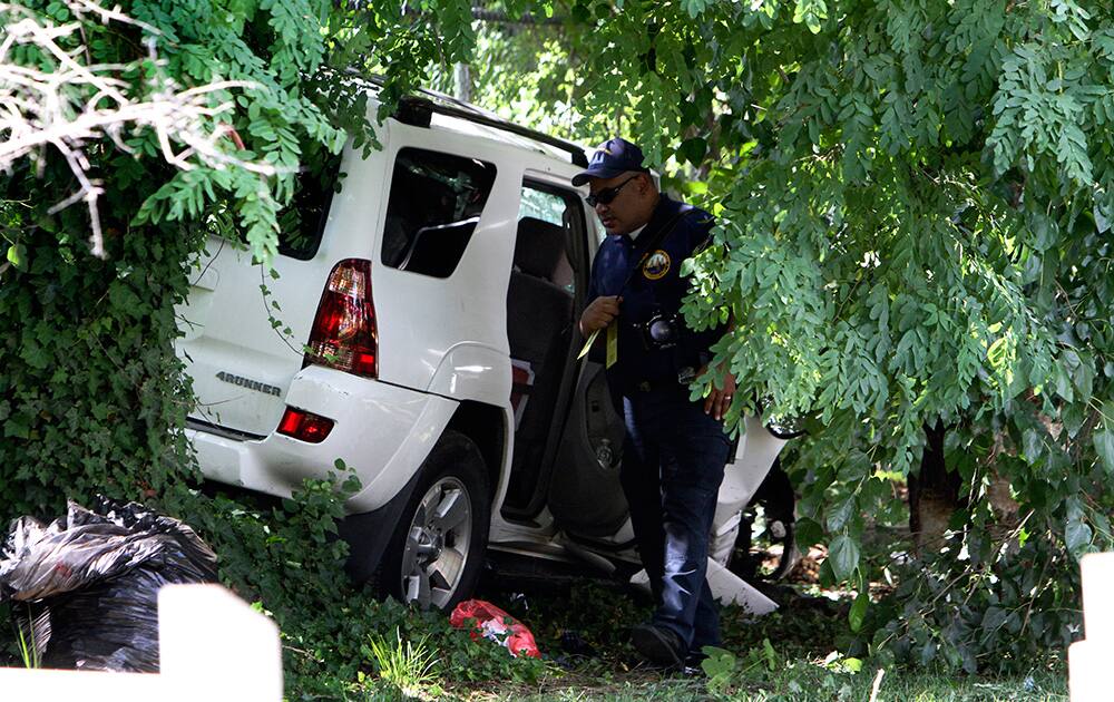 Investigators gather at the scene of a fatal accident in North Philadelphia. Two children were killed and three people critically injured when a hijacked car lost control and hit a group of people near a fruit stand, according to police.