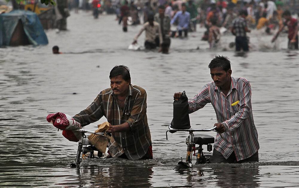 Men push their bicycles as they wade through a water- logged area after heavy monsoon rains in Ahmadabad.