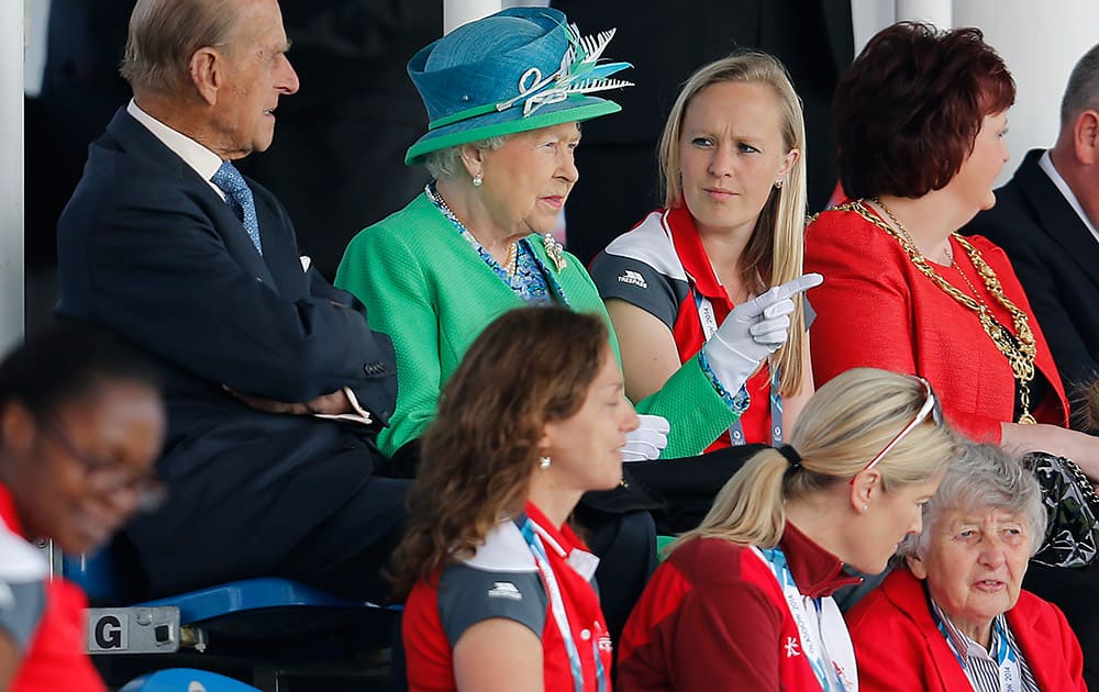 Britain`s Queen Elizabeth II , center, and Prince Philip, Duke of Edinburgh, left, sit to watch hockey at the Commonwealth Games 2014 in Glasgow, Scotland.