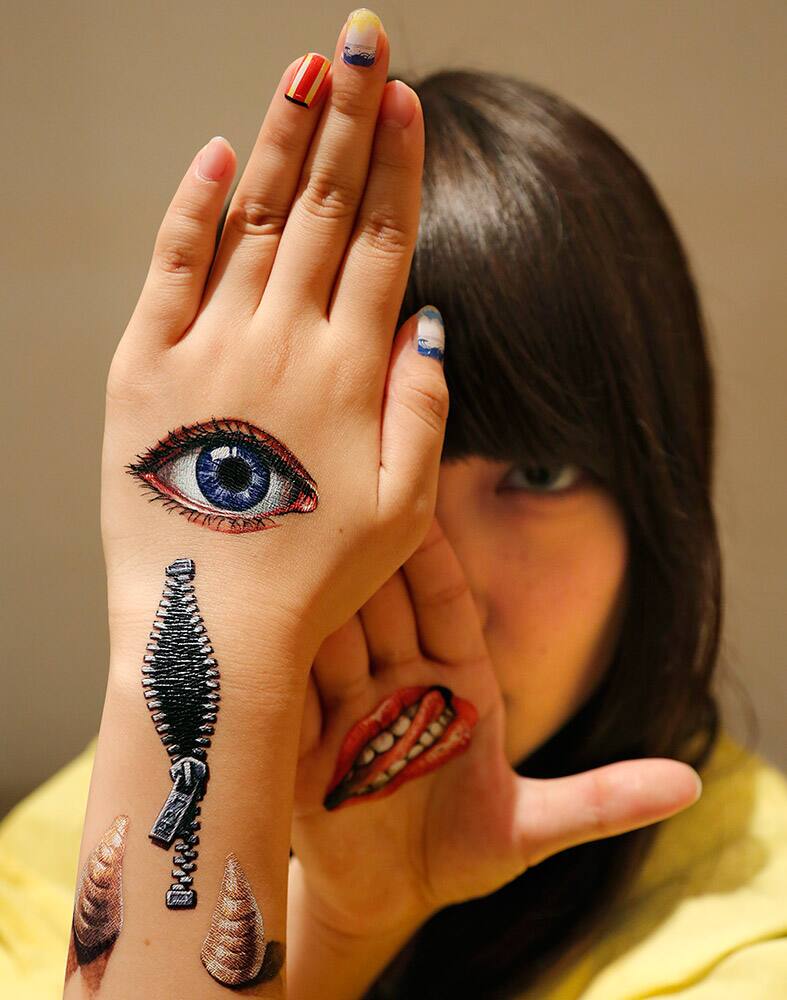 Musashino Art University student Kana Ogawara displays body paintings by Hikaru Cho on her hands at an art event in Tokyo.