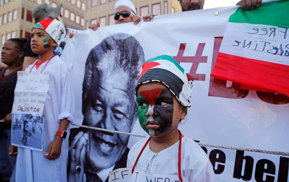 A child, center, next to the face of former South African President Nelson Mandela as he forms part of the Palestinian supporters taking part in a rally against the Israeli occupation of the Palestinian territories in Cape Town, South Africa.