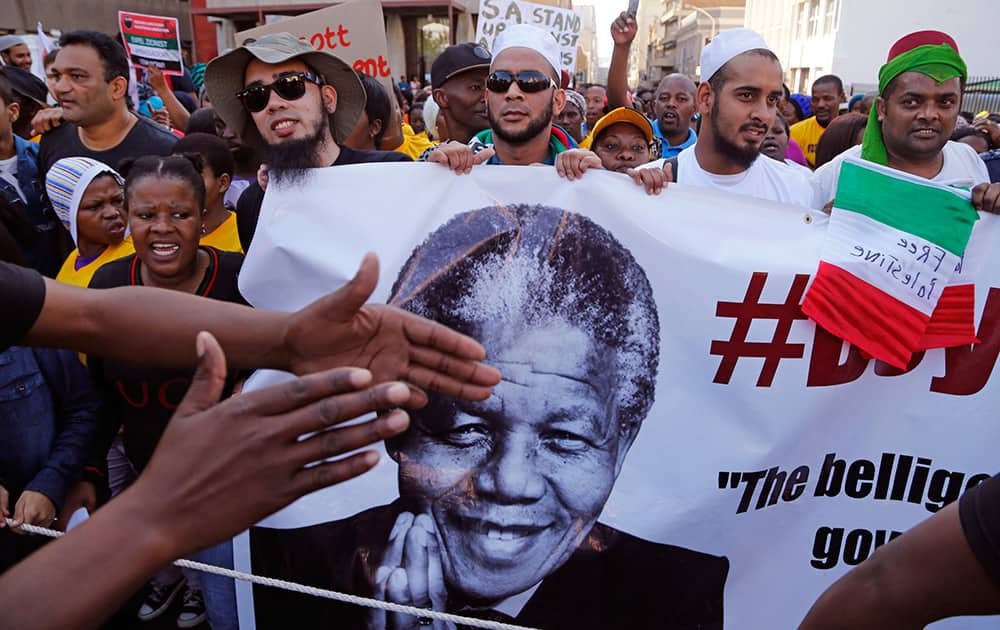 A man`s hands, left, covers part a banner with the face of former South African President Nelson Mandela, as he takes part with other Palestinian supporters, in a rally against the Israeli occupation of the Palestinian territories in Cape Town, South Africa.