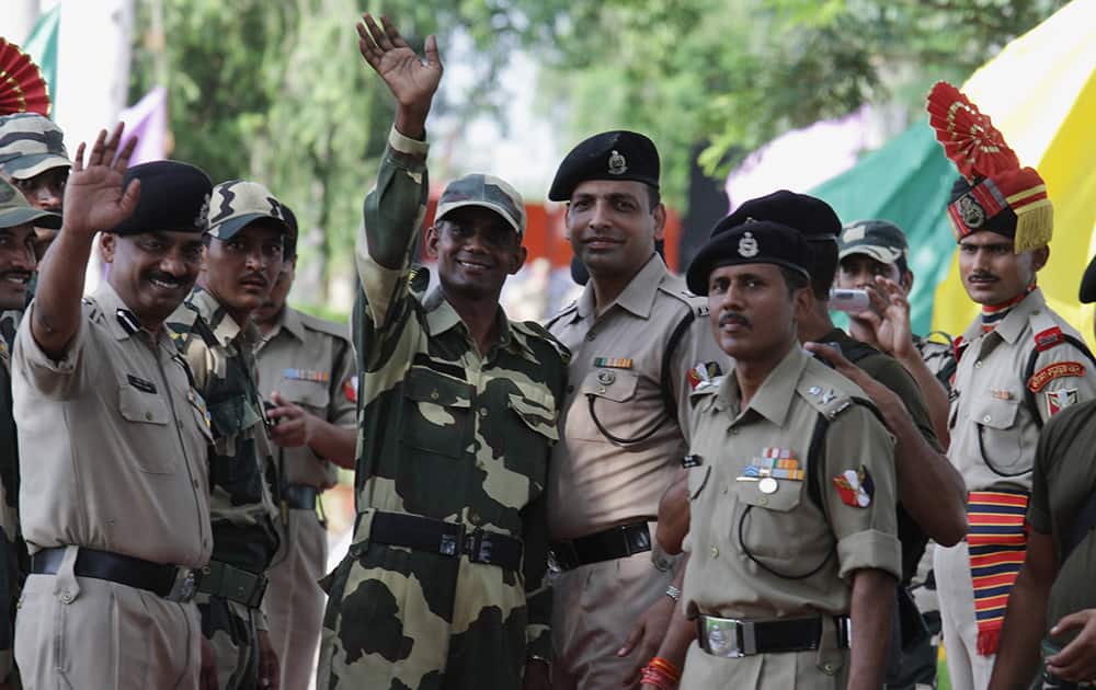 Indian soldiers receive Indian border guard Satyasheel Yadav, center, after crossing into the Indian territory, as Yadav waves back at the Sialkot border post in Punjab province, Pakistan.