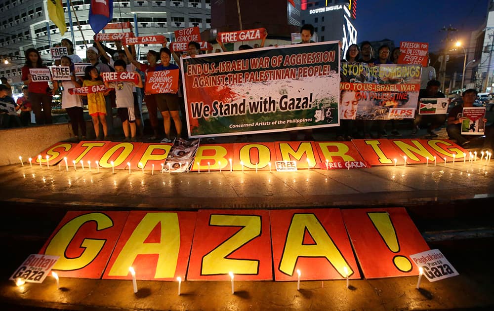 Protesters display placards behind a `Stop Bombing Gaza!` message after lighting candles, in suburban Quezon city, northeast of Manila,