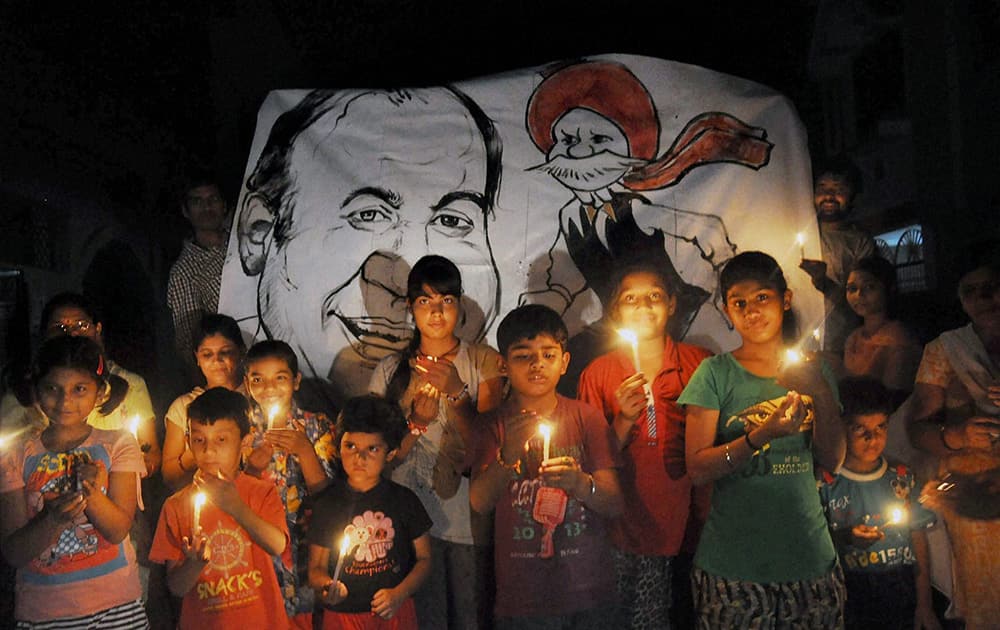 Children holding candles in the backdrop of a poster of cartoonist Pran Kumar Sharma and his creation Chacha Chaudhary painted by them to pay homage to the cartoonist who passed away in Moradabad.