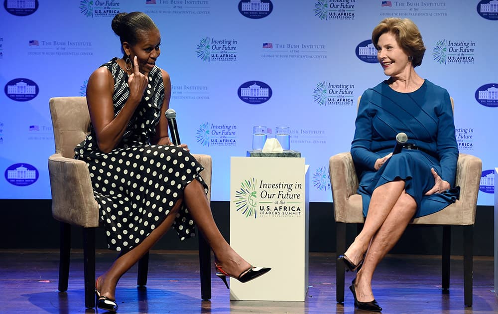 First lady Michelle Obama, left, points out her hairstyle as she sits with former first lady Laura Bush as they participate in the `Investing in Our Future` a discussion at the Kennedy Center in Washington.
