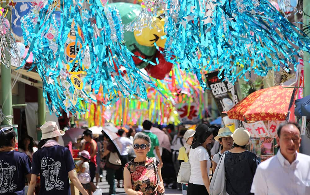 People walk under colorful paper streamers for the Tanabata Star Festival at Asagaya in Tokyo.