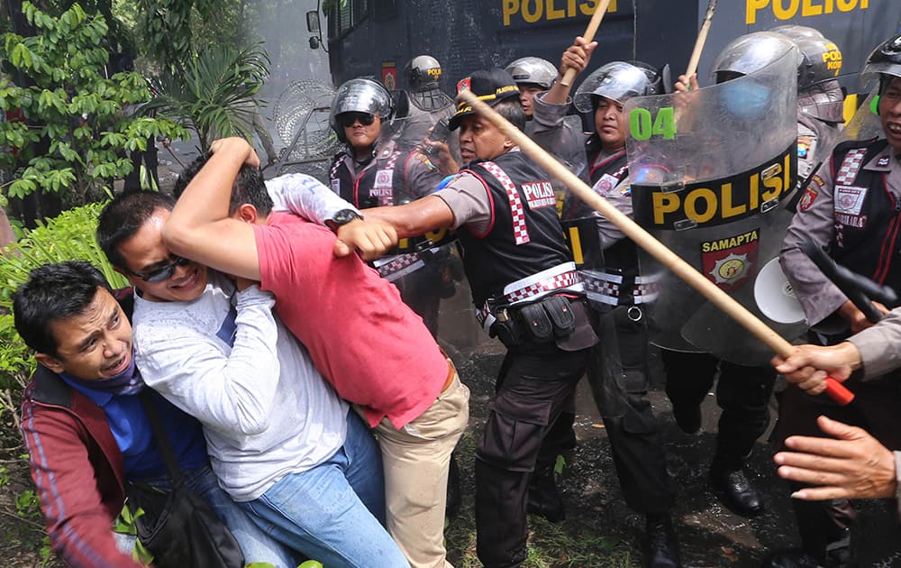 Supporters of losing presidential candidate Prabowo Subianto try to protect themselves from the riot police in a scuffle during a protest outside the local office of the General Election Commission in Surabaya, East Java, Indonesia.
