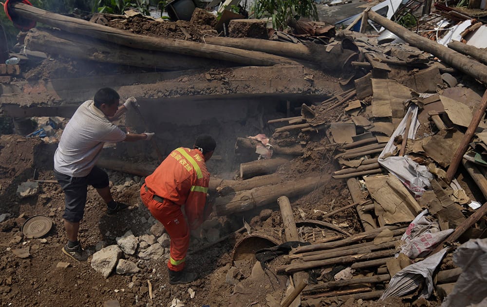 A villager helps a rescuer as they look for missing persons amid the rubble of destroyed houses following an earthquake in the town of Longtoushan in Ludian County in southwest China`s Yunnan Province.