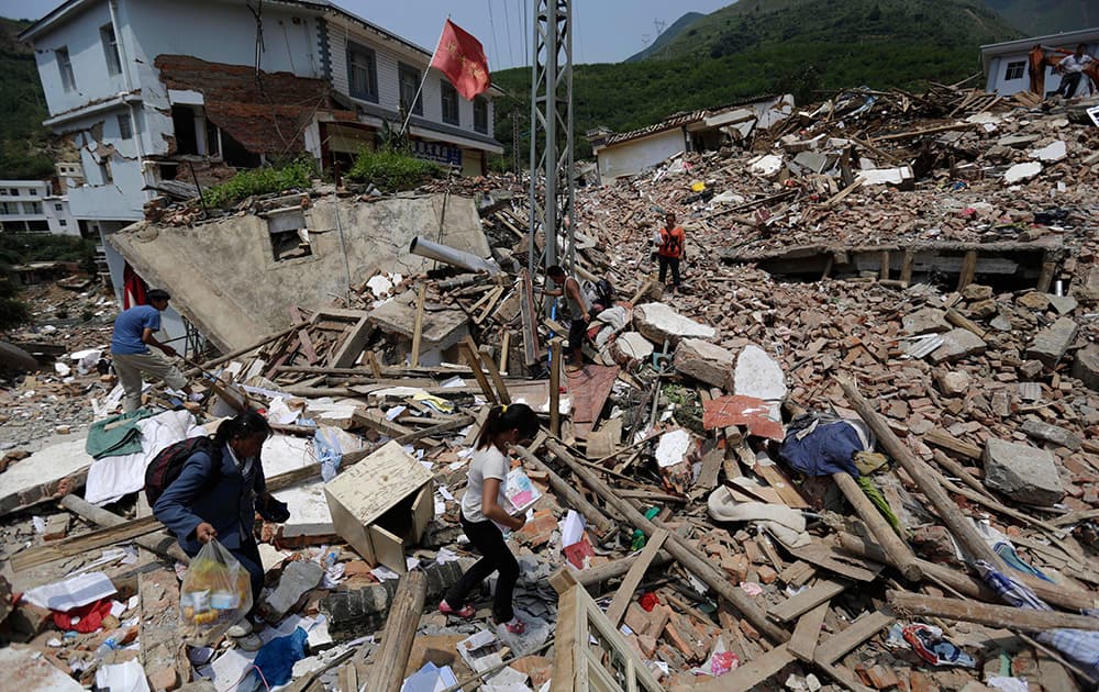 Villagers carry their belongings past the rubble of destroyed houses in the quake hit town of Longtoushan in Ludian County in southwest China`s Yunnan Province.