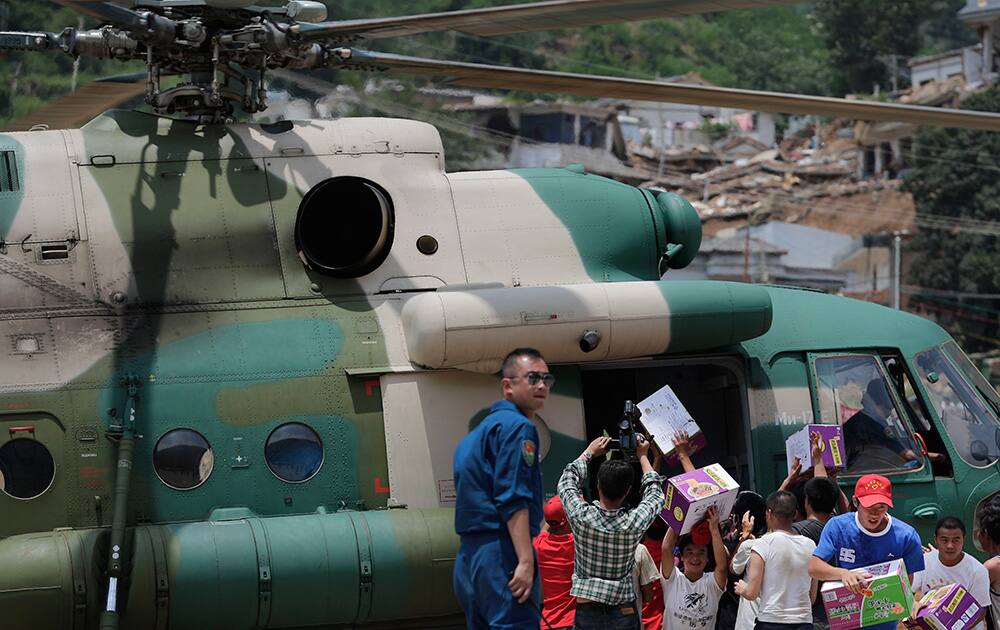 Volunteers deliver suppliers transported by a helicopter to the earthquake-hit Longtoushan town in Ludian county in southwest China`s Yunnan province .