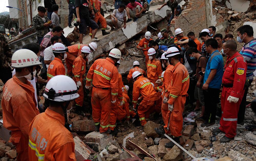 Rescuers try to retrieve a trapped victim`s body from a collapsed house following a massive earthquake in the town of Longtoushan in Ludian County in southwest China`s Yunnan Province.