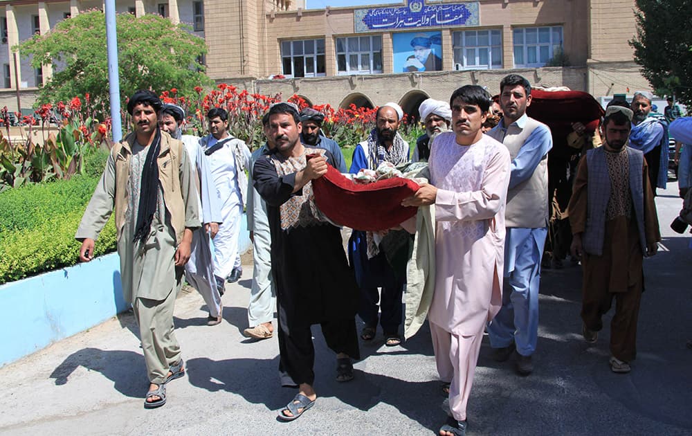 Afghan men carry a dead body during a protest against US and Afghanistan`s officials, in Herat, west of Kabul, Afghanistan.