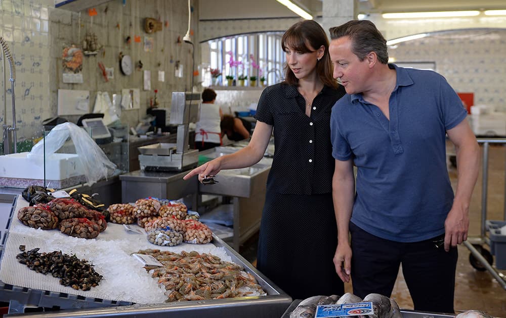 Britain`s Prime Minister David Cameron, right, and his wife Samantha, pose for photos as they a visit a seafood market, during their summer vacation, in Cascais, Portugal.