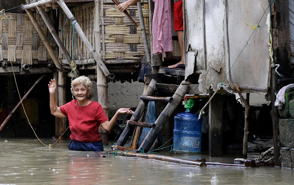Residents go on their daily business on a flooded street after monsoon rains that was induced by Typhoon Halong at Hermosa township, Bataan province in northwestern Philippines.
