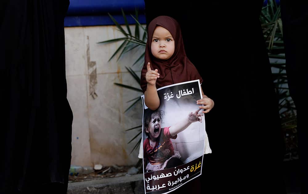 A Bahraini child holds a poster with Arabic that reads, `children of Gaza, Gaza: A Zionist aggression and an Arab conspiracy,` during a rally in support of Gaza, outside a religious community center in Diraz, Bahrain.