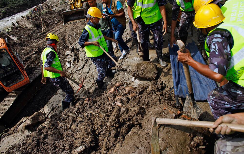 Nepalese policemen look at the body of a landslide victim under the debris after they found during their search operation in Mankha village, about 120 kilometers (75 miles) east of Katmandu, Nepal.