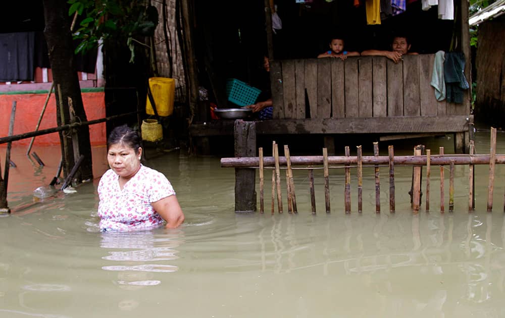 A woman wades through a road overflown by the Bago river as her family members look from their residence at a low-lying part in Bago, 80 kilometers (50 miles) northeast of Yangon, Myanmar.