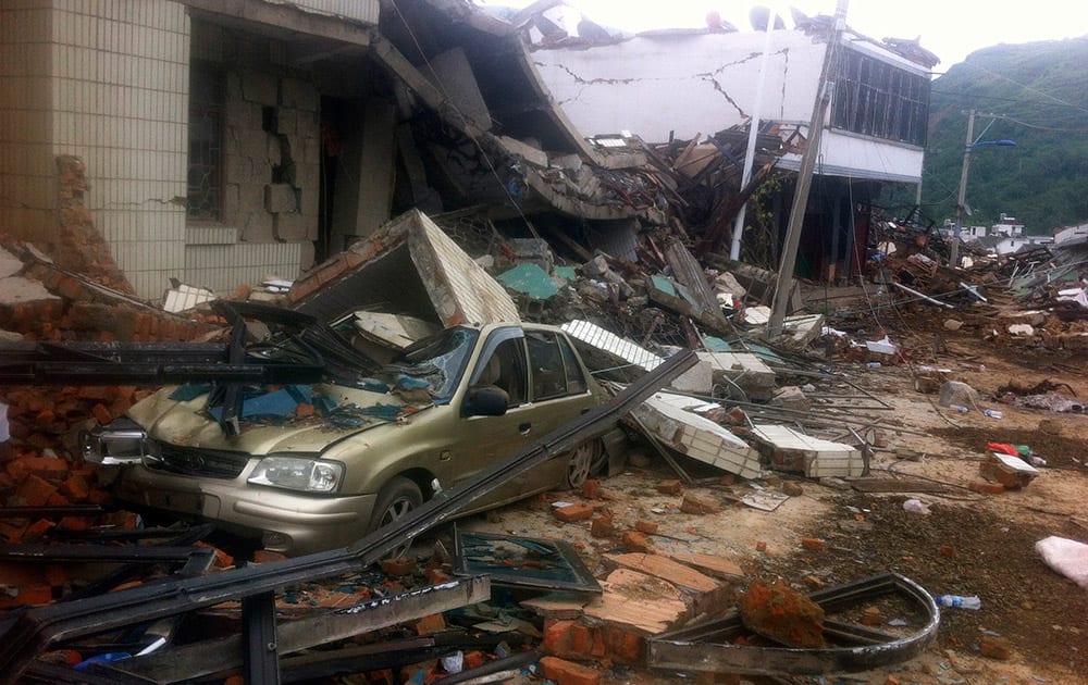 A car is crushed by a collapsed building in the epicenter of an earthquake that struck the town of Longtoushan in Ludian county in southwest China`s Yunnan province. Rescuers dug through shattered homes Monday looking for survivors of a strong earthquake in southern China`s Yunnan province that toppled thousands of homes on Sunday, killing hundreds and injuring more than a thousand people.
