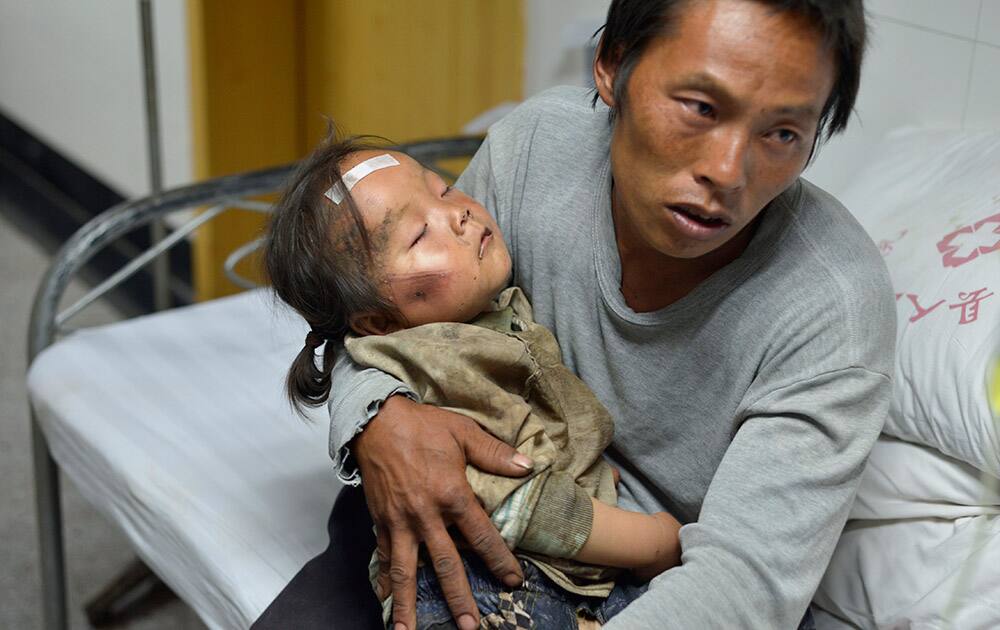 A man holds an injured child receiving medical treatment at a hospital following an earthquake in Ludian county in southwest China`s Yunnan province.