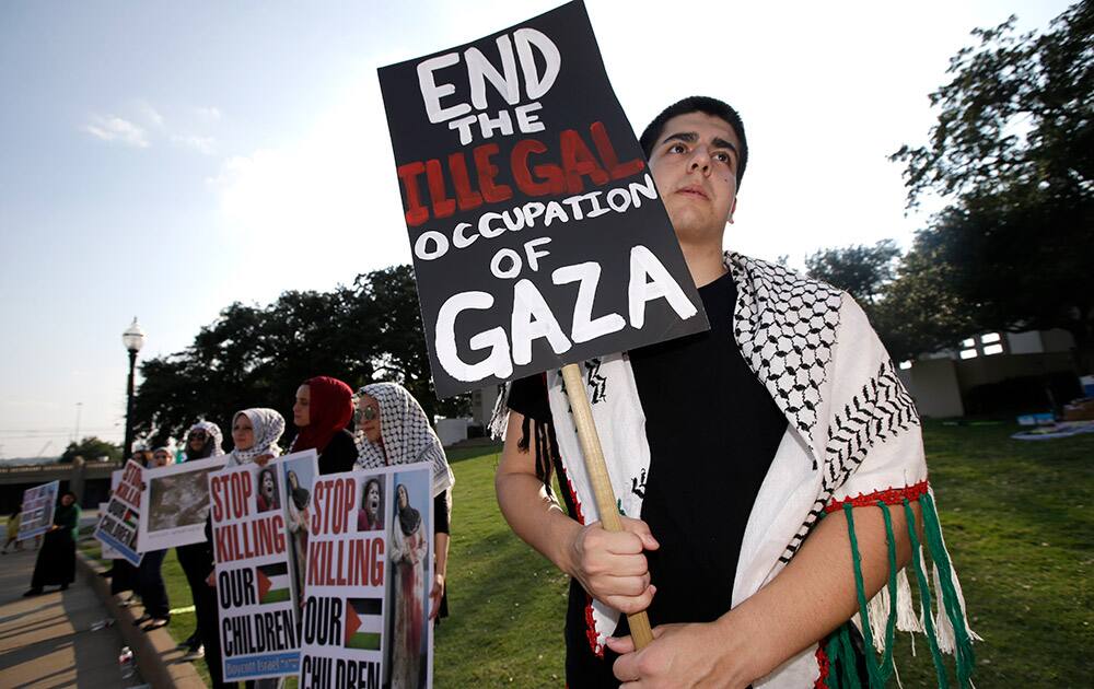 Logan Bowers holds a sign that reads, End The Illegal Occupation of Gaza, during a pro Palestinian protest at Dealey Plaza, in Dallas.