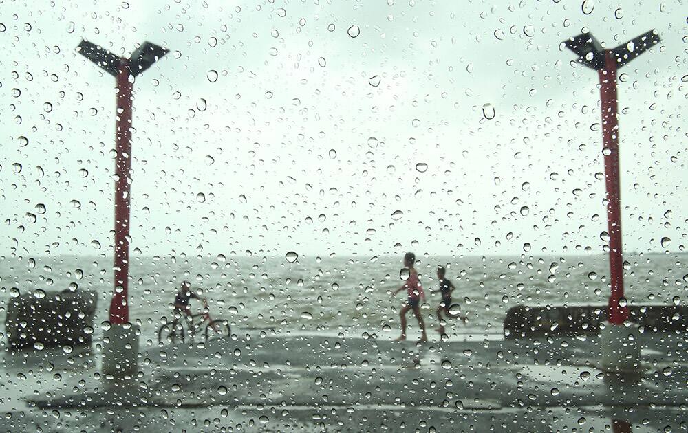 Filipino children play in the rain at a public park in suburban Navotas, north of Manila, Philippines.