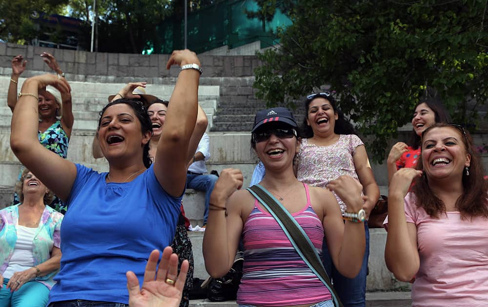 Turkish women laugh during a yoga session in a public garden in Ankara, Turkey, in protest against Turkey`s deputy prime minister Bulent Arinc.