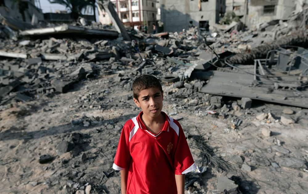 A Palestinian boy stands on debris from destroyed houses, hit in an overnight Israeli strike, in Gaza City, northern Gaza Strip.