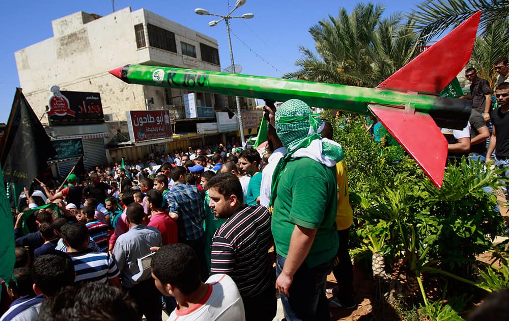 A supporter of Hamas holds a representation of a rocket as others shout slogans against the Israeli attack on the Gaza Strip, during a protest in the West Bank town of Tulkarem town.